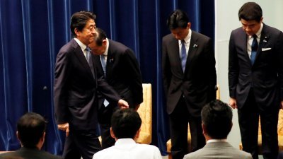 周五在国会逃过不信任投票的日本首相安倍晋三（左），在例行记者会后，轻松离开会场。