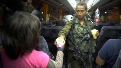 以色列周日派军到叙利亚，协助救援组织“白头盔”的家属撤离。在巴士上，一名以色列女士兵，给他们派水。