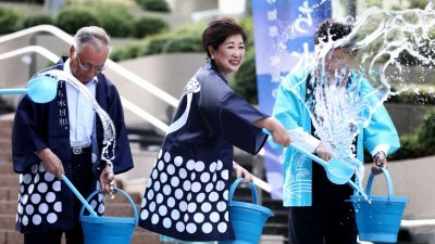  东京都知事小池百合子（中）周一在东京举行的一次名为Uchimizu的泼水活动中泼水。泼水降温是江户时代用来抗暑的传统方法。-法新社-