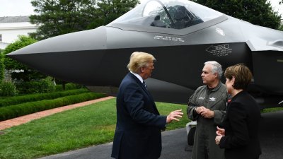 白宫在南草坪展示F-35战机模型，总统特朗普（左）与洛克希德马丁公司董事兼首席测试飞行员诺曼（中），以及主席兼首席执行员休森交谈。-法新社-