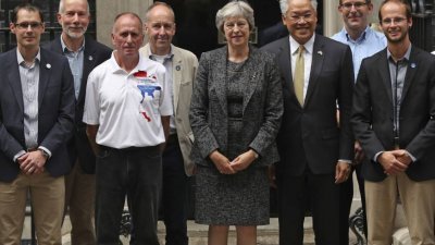英国首相特丽莎梅（中）与泰国驻英大使（右2），以及参与救援任务的人员在首相府外合影。