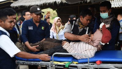 印尼救援人员周一在林贾尼山脚下的桑巴伦村，将一名成功下山的女登山客抬上担架送往救治。