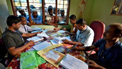 阿萨姆邦其中一间国家公民登记中心里，官员们正为排队的民众查看名册。印度中央与阿萨姆邦政府皆承诺，未被认可的400万“非法居留的外国人”，在9月底前还有提出复审与上诉的机会。