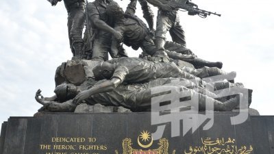 陈保山少校（左3）带领众退伍军人在国家英雄纪念碑前敬礼。左起为姆鲁克亚安迪少校、巴尔德少校、潘贤森少校（海军）、拿督吴成都准将（空军）、郑高飞少校（陆军）。 （摄影：颜泉春）