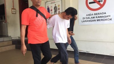 21岁的被告莫哈末札里纳札（中）与次被告（右）在警方押送下步出法庭，低头躲避镜头。