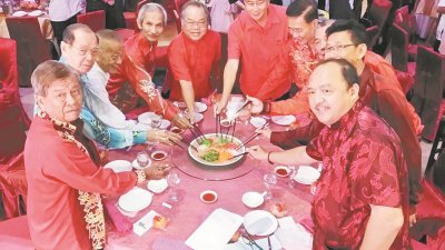 郑东旺（左5起）和李官仁在拉律马登及司南马发展华小工委会举办的新年团拜上，与其他主桌嘉宾一同捞生欢庆。