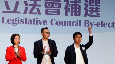 香港泛民主派候选人区诺轩（右），在周日的补选中拿下了港岛区，他在台上举拳庆祝胜选。