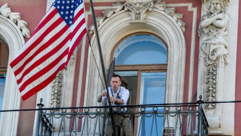 俄罗斯关闭美国驻圣彼得堡总领事馆，一名美方工作人员在离开前，把悬挂在领事馆外的美国国旗固定好。