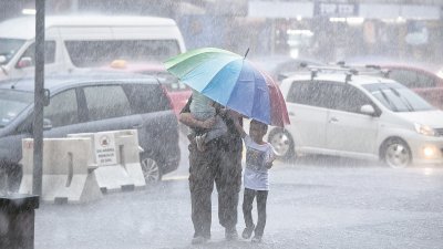 吉隆坡周二午后下起倾盆大雨。图中一名父亲撑著雨伞，小心翼翼将两名孩子护在伞下避免淋雨。
