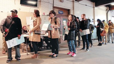 密歇根州底特律一处设于消防局的投票站，选民在耐心排队轮候投票，并细读当局派发的资料。