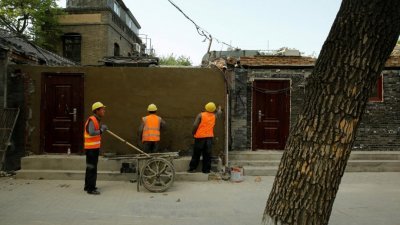 3名工人在靠近北京故宫的胡同附近一所房子，竖起一堵墙。