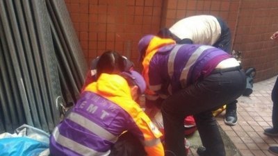 救援人员为堕楼的男生急救。（图取自《东网》）