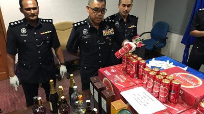 三苏（中）在立功警官的陪同下，向媒体展示由警方所缉获的“Kingfisher”啤酒。