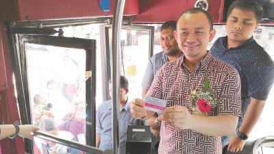 马智礼出示免费申请的“希望巴士”卡，呼吁当地民众善用这一免费服务，同他也是新邦令金区的“希望巴士”第一名乘客。