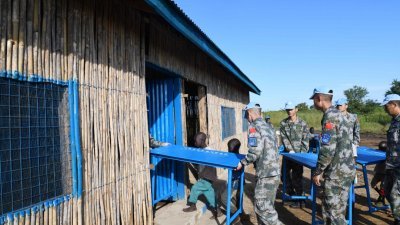 中国维和步兵营官兵在南苏丹首都朱巴，修缮一所小学校舍。这是中国维和官兵和学生将桌椅搬进教室。