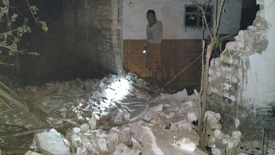 在东爪哇苏民纳地区， 一所民宅的墙壁在强震中倒塌，灾民在漆黑中持手电筒查看损失。