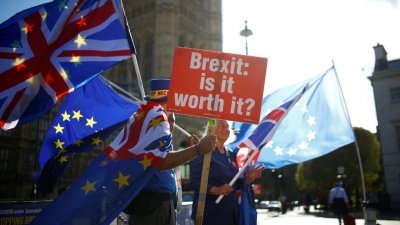 英国民众在伦敦的议会大厦前，举著英国与欧盟的旗帜，对英国脱欧计划表示抗议。其中一名民众手中持著“脱欧：这值得吗？”的标语。