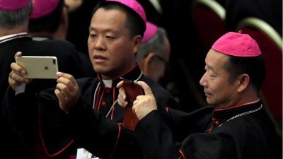 到梵蒂冈出席世界主教会议的中国主教郭金才（左）和杨晓亭，在等待教宗方济各到场时，拿起手机拍照。