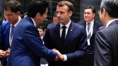 法国总统马克龙（中），周五抵达欧亚首脑会议会场时，与一众与会领导人打招呼。这是马克龙和日本首相安倍晋三握手寒暄。