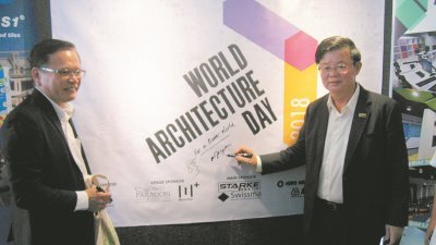 骆泽扬（左起）和曹观友，在世界建筑日的大型海报上签名。