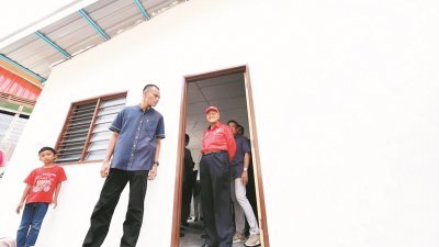 首相敦马哈迪（右）周六在浮罗交怡瓜拉德亮巡视一间遭风灾严重破坏后获重建的屋子。