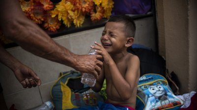 一名洪都拉斯男童因长时间长途跋涉以致脚痛流血，周二在墨西哥边界城镇停下来休息时，忍不住嚎啕大哭。
