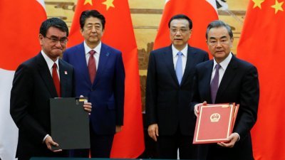 在日本首相安倍晋三（左2）与中国总理李克强（右2）的见证下，中国外交部长王毅（右）与日本外交部长河野太郎，出席了在北京人民大会堂的签约仪式，两人各自手持黑色及红色的协议书。