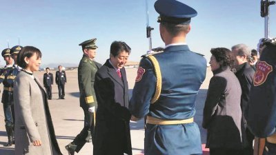 日本首相安倍晋三（中）与夫人周六结束为期三天的访华行程，在北京国际机场乘搭专机返回东京。他在上机前与到场送机的官员道别。