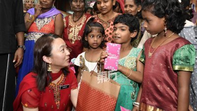 杨巧双（左）出席敦依斯迈医生花园巴刹举办的2018年屠妖节庆典推介礼时，派发紫包予印度儿童。 （摄影：伍信隆）