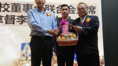 李官仁（左）接领郑东旺赠送的水果篮，中为工委会主席张文兴。