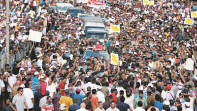 斯里兰卡反对派支持者，因政府无法兑现3年前上台执政时作出的承诺，周三在首都可伦坡主要街道举行大规模示威游行。身穿红衣的前总统拉贾帕克萨（坐车者）向他的支持者挥手致意。