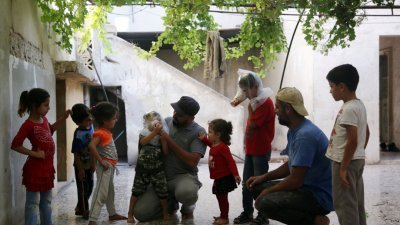 住在伊德利卜南部村庄的沙哈德（中），教导孩子们如何套上自制的简易防毒面具，引来孩童们好奇围观。根据联合国，叙利亚政府军去年多次使用包括“氯”在内的化武。