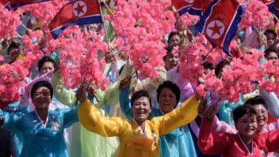 参与国庆游行的朝鲜妇女，身穿传统韩服，手拿国旗及粉色花束，脸带笑意地欢庆国庆。朝鲜今年的国庆阅兵仪式，少了火药味，虽然还有一些反美标语，但没有展示对美国具攻击性的洲际导弹。