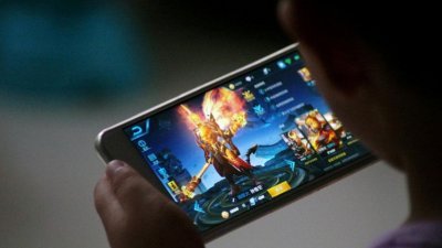腾讯开发的《王者荣耀》是收入最高的手机游戏，仅在中国就有2亿的月活跃用户，有不少中小学生沉迷其中。这是中国山东省一名孩童，玩著《王者荣耀》。
