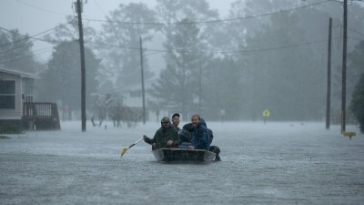 飓风“弗洛伦斯”侵袭美国东岸期间，来自北卡罗来纳各地的志愿者，于周五在被洪水淹没的新伯尔尼市灾区划著船，帮助受困的民众。