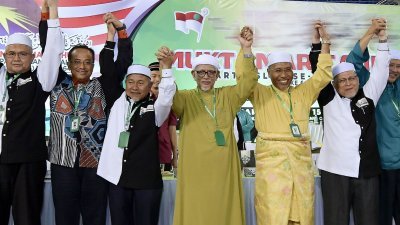 哈迪阿旺（中）在伊党代表大会闭幕时，与中央领导层一起高举双手示意。