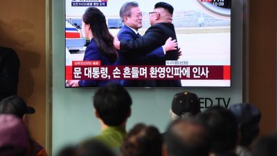 在韩国首尔火车站的电视荧幕上，民众们看著现场直播朝鲜最高领导人金正恩拥抱迎接到访的韩国总统文在寅。