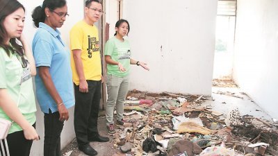 王丽丽（右起）与陈润辉 巡视被废置的宝玉花园组 屋区，发现顶楼的单位， 垃圾堆积如山。