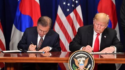 韩国总统文在寅（左）与美国总统特朗普签署新版本的美韩自由贸易协定。