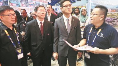 再里尔（左3）在陈国良（左2）及马来西亚旅游总会首席执行员潘在能（左）陪同下，走访旅游展销会摊位，听取职员介绍优惠的旅游配套。