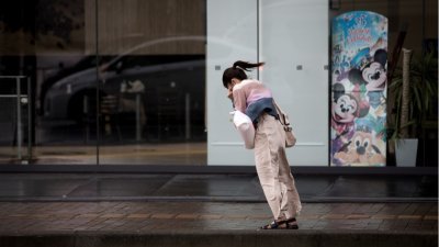 在九州鹿儿岛市的大街上，可见一名女子几乎使出全力，试图逆风前行。