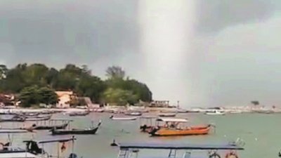 民众在丹绒道光海边使用手机拍下海上出现水龙卷的情景。
