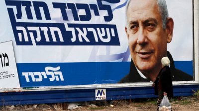 在以色列北部城市海法，一名以色列阿拉伯妇女途径印有总理内塔尼亚胡肖像的竞选广告牌。