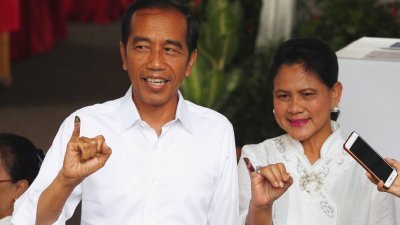 印尼总统佐科周三上午与夫人伊丽安娜，到雅加达的投票所投票。夫妇俩在投票后，向记者展示醮上墨汁的手指。-路透社-
