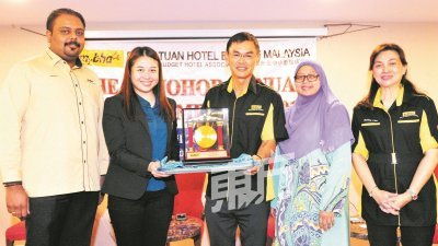 马来西亚中小型旅店协会柔佛分会周六召开第12届常年会员大会，李延富（左3）赠送纪念品给开幕人廖彩彤（左2）。左起为斯里加纳斯、兹涵和李惠芳。（摄影：杨金森）