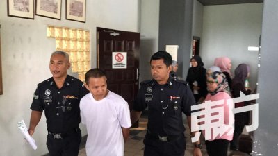 被告被两名庭警带离马六甲第一高庭时，一脸木然。（摄影：魏美琪）