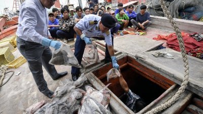 慕哈末苏菲（右）从被取缔的越南渔船中，取出一件件扣押物品。（图取自：马新社）
