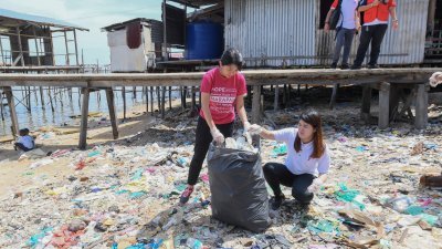 杨美盈（左）前往山打根为黄诗怡助选之馀，在出席环境部举办的反塑料活动上，她与黄诗怡一同捡起被丢弃在沙滩上的塑料罐子。