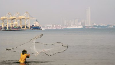 一名渔夫在北海的清洁海滨撒网捕鱼，但眼前的景物却因烟霾而变得朦胧一片。
