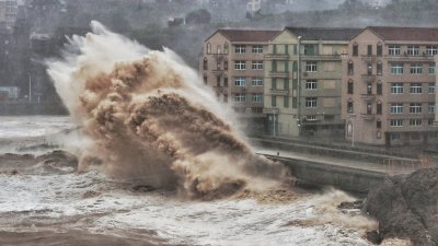 台风在浙江省台州市沿海掀起汹涌海浪，高度与建在海边的6层高楼房相当，场面骇人。